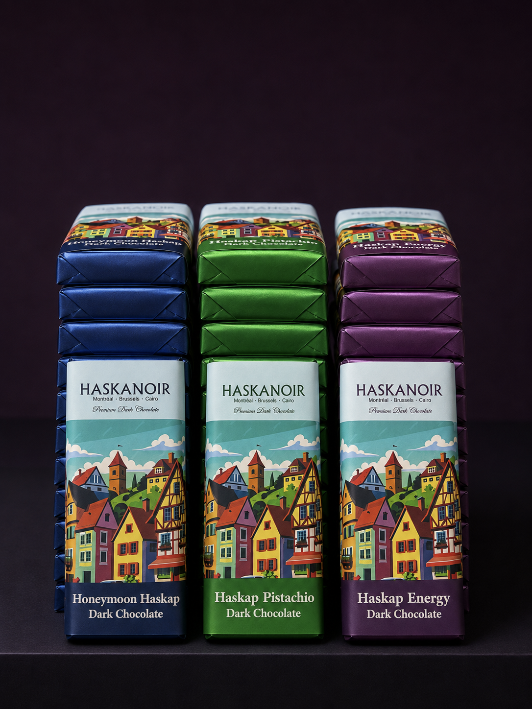 Stacks of HaskaNoir Honeymoon, Pistachio and Energy bars in their blue, green and purple wrappers